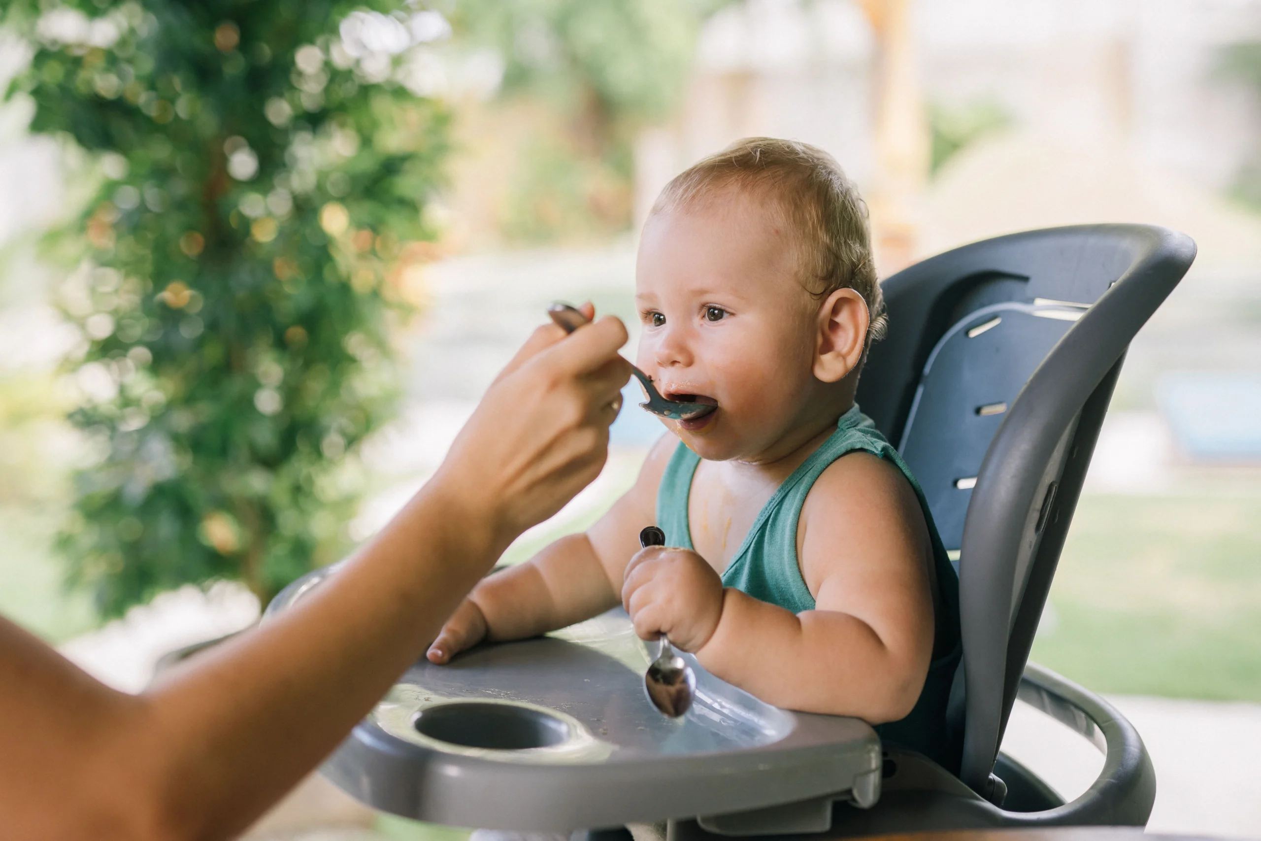Un bébé dans une chaise haute qui découvre les aliments grâce à la diversification par Manalait