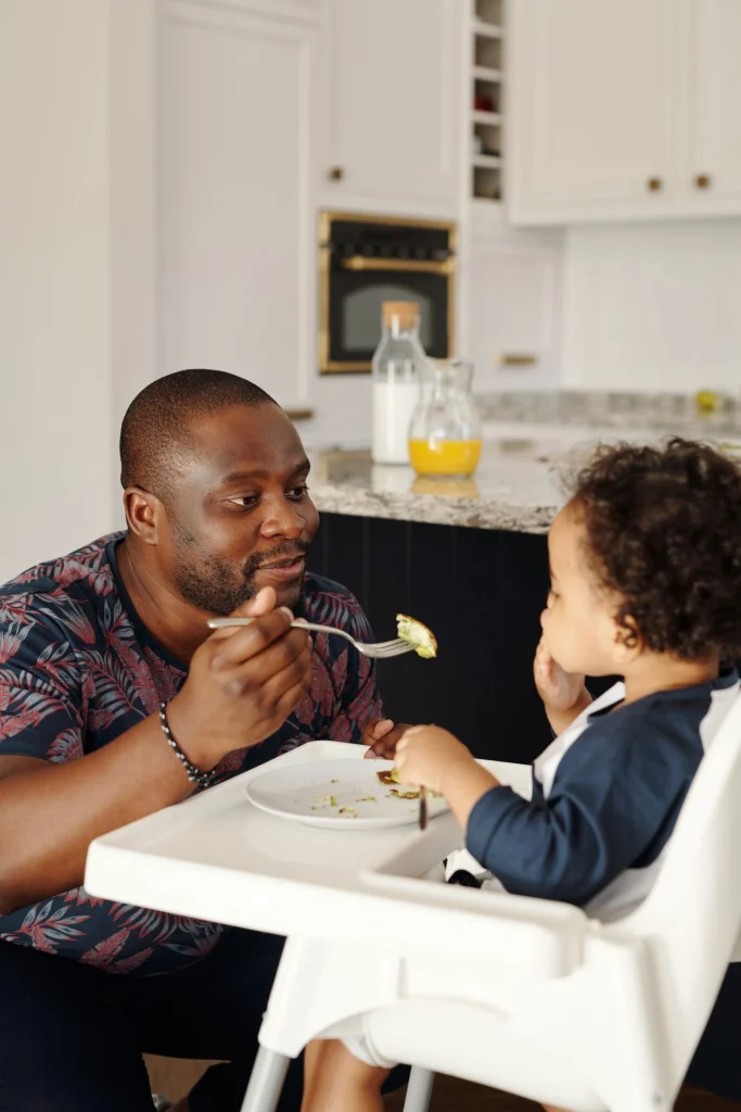 Papa noir qui donne à manger à son fils un morceau avec une fourchette